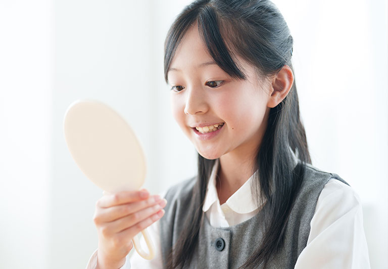 鏡で歯を見る女の子